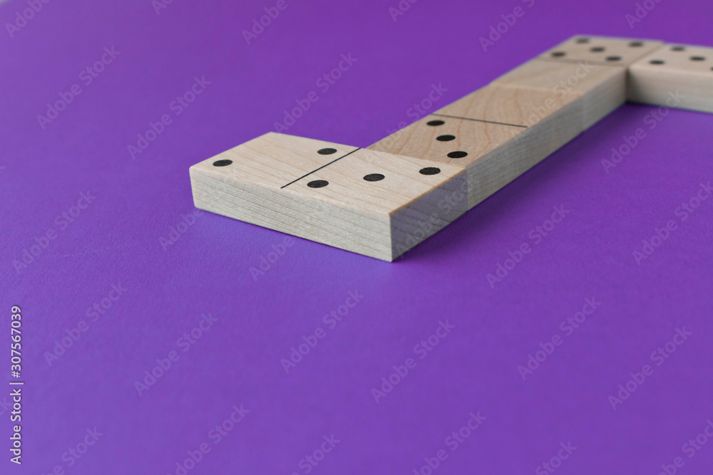 Playing dominoes on a purple background. Leisure games concept. Domino effect. Playing dominoes on a purple background. Leisure games concept. Domino effect.