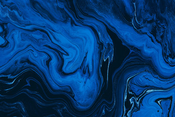 Hand painted background with mixed liquid blue and golden paints. Classic blue color of the year 2020. Abstract fluid acrylic painting. Marbled blue abstract background. Liquid marble pattern