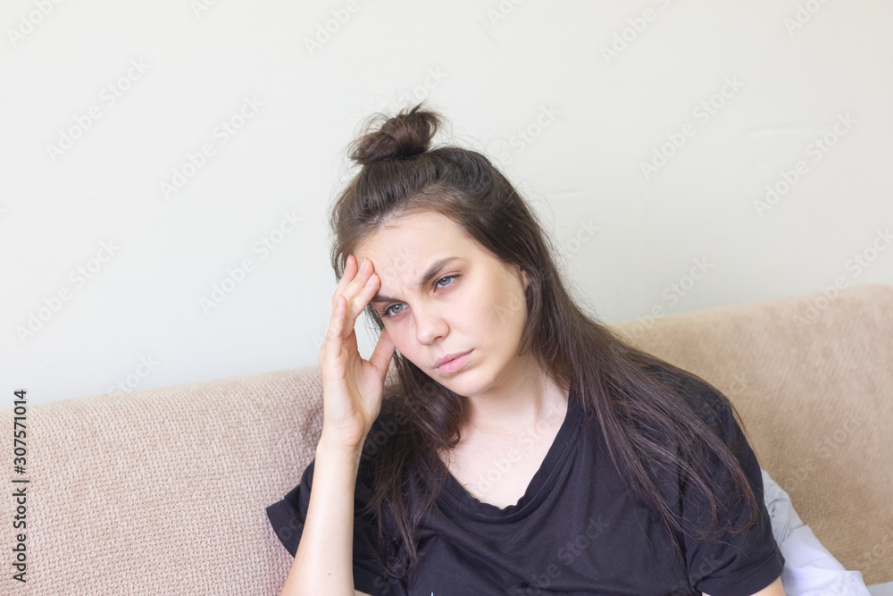 Sick young woman sitting at home with severe headache