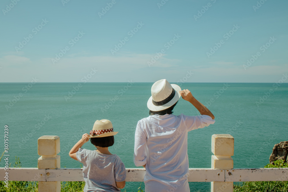 Summer Vacation and Travel Trip Concept : Asian woman and girl standing relax on cliff, They looking forward to sea and feeling happiness.