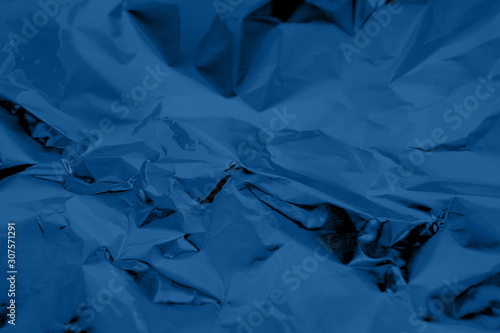 Abstract trendy dark blue colored crumpled foil texture background. 2020 color trend concept.