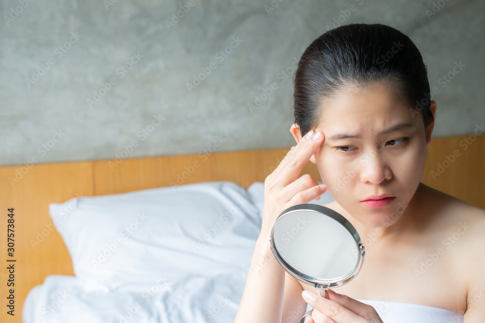 Portrait of Asian woman worry about her face when she saw the problem of wrinkle and age spots by the mini mirror. Conceptual shot of problem skin on female face. Portrait of Asian woman worry about her face when she saw the problem of wrinkle and age spots by the mini mirror. Conceptual shot of problem skin on female face.