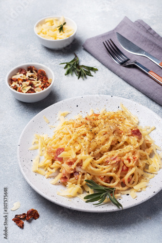 Pasta spaghetti with bacon egg cheese on a plate with spices. Traditional Italian dish Carbonara. Grey concrete table