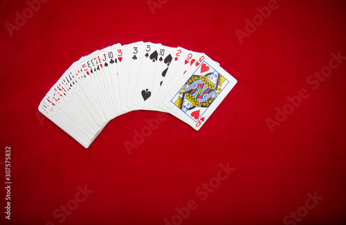 Deck of playing cards on red color velvet background. Top view with copy space.