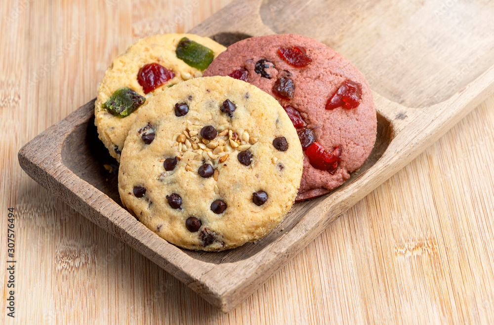 Chocolate chip cookie and mixed fruits cookie with wooden tray on the wood table. Delicious homemade baked cookie. Chocolate chip cookie and mixed fruits cookie with wooden tray on the wood table. Delicious homemade baked cookie.