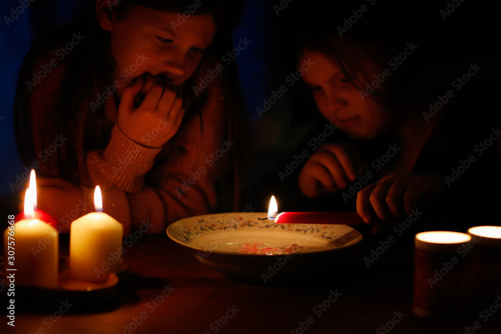 Magical two children divine with candles in dark Magical two children divine with candles in dark