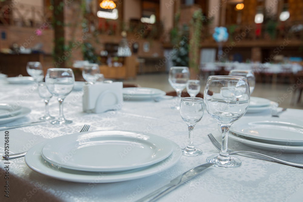 Tables set for meal . fork, knife . empty glasses and plates on the table in the restaurant . Tables set for meal . fork, knife . empty glasses and plates on the table in the restaurant .