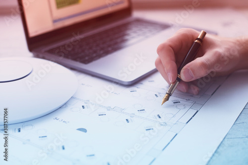 Engineering process. Man developing a network diagram for wifi access in cafe. Access point, floor layout, laptop and man hand on the bright background. Space for your text.