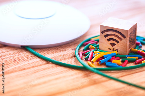 Access point with bright cables connected on it on the wooden background. Space for your text.