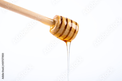 Honey and honey wooden dipper on white background