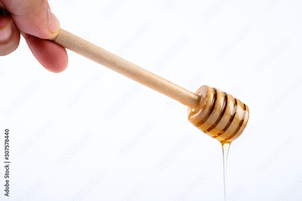 Hand hold honey wooden dipper with honey on white background