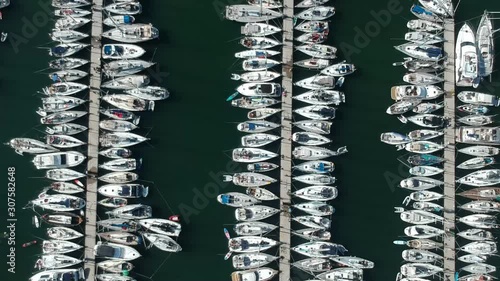 Aerial marina with three piers packed full of white sailboats on dark water a sunny day photo