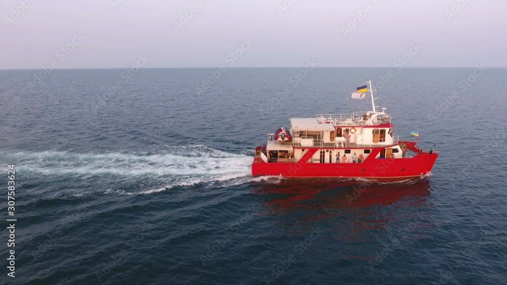 Aerial view. Research ship is sailing past in open ocean. Red catamaran goes on two engines Aerial view. Research ship is sailing past in open ocean. Red catamaran goes on two engines