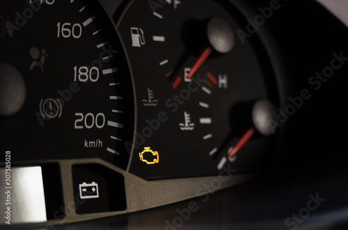 Canvas Print Yellow lit engine error sign on car dashboard close up