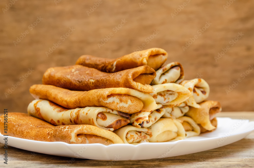 Pancakes with filling stacked pyramid on a white plate, standing on a wooden background close-up Pancakes with filling stacked pyramid on a white plate, standing on a wooden background close-up