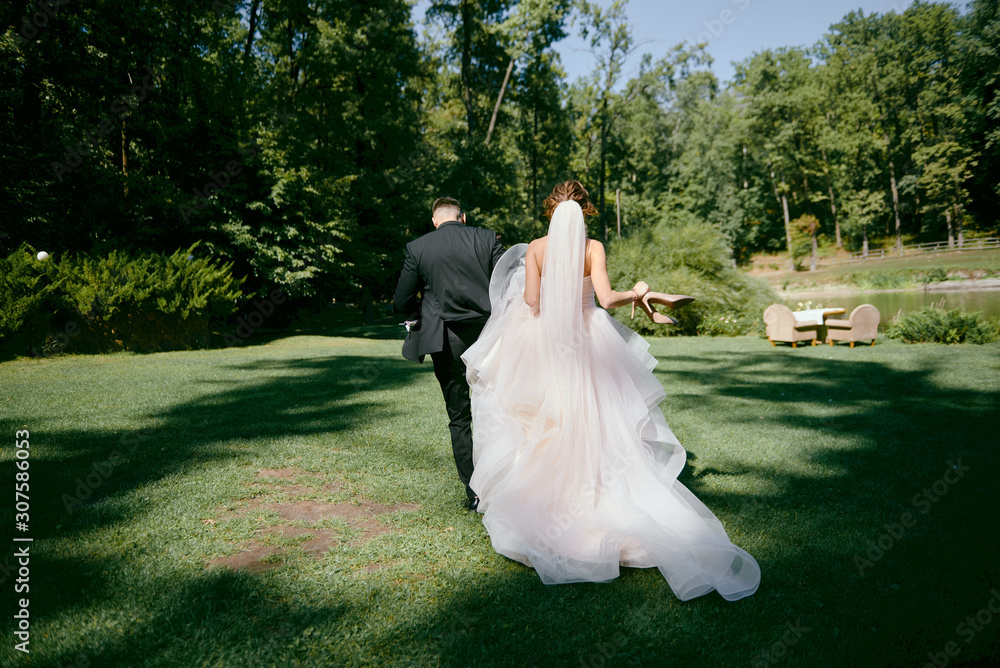 Full length body portrait of young bride and groom walking in park ...