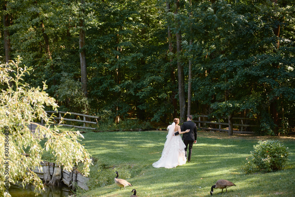 Full length body portrait of young bride and groom walking in park ...