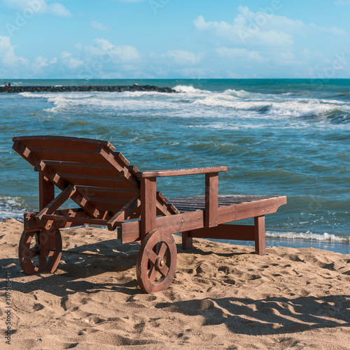 deck chair on a sunny sandy beach amid the oncoming waves of the Tyrrhenian Sea