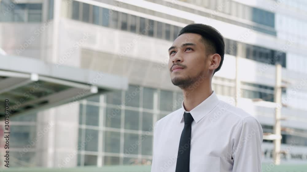 Young asian businessman stand and looking at the surrounding building in the morning Young asian businessman stand and looking at the surrounding building in the morning