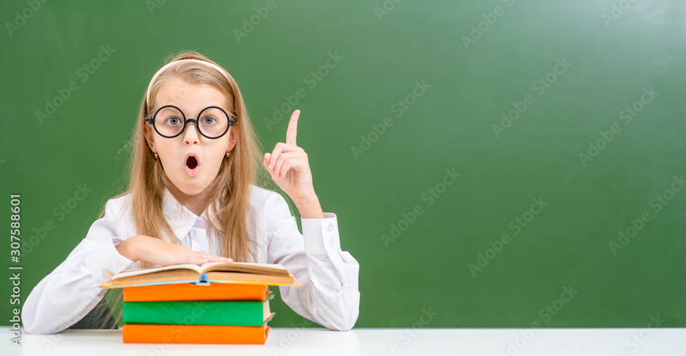 Surprised young girl wearing a funny eyeglasses sits in classroom and has idea. Success, idea and creative concept Surprised young girl wearing a funny eyeglasses sits in classroom and has idea. Success, idea and creative concept