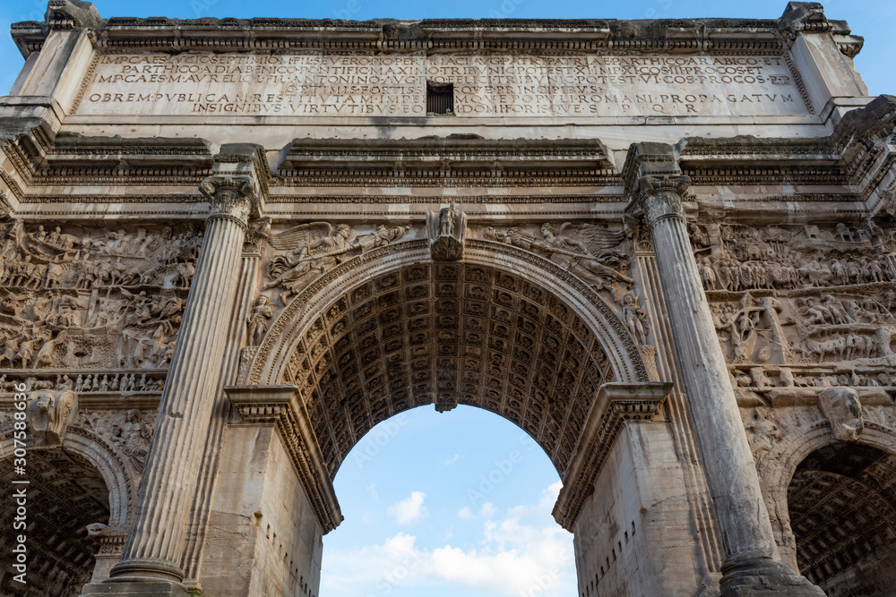 Obraz premium Arch of Septimius Severus at the northwest end of the Roman Forum. White marble triumphal arch
