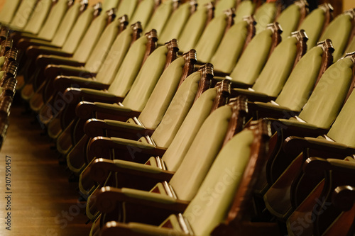 Photograph of the Rows of theatre seats. beige soft velvet chairs in the theater hall