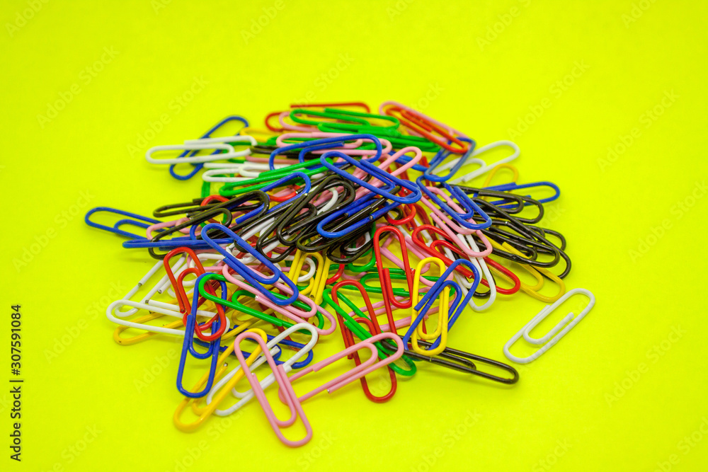 A large pile of multi-colored paper clips closeup on a green background. A large pile of multi-colored paper clips closeup on a green background.
