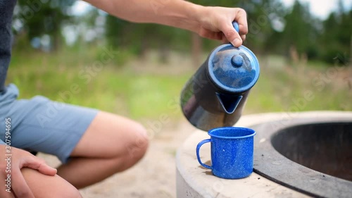 Campsite with man closeup pouring tea from teapot on grill in Flaming Gorge, Utah summer camground in morning photo