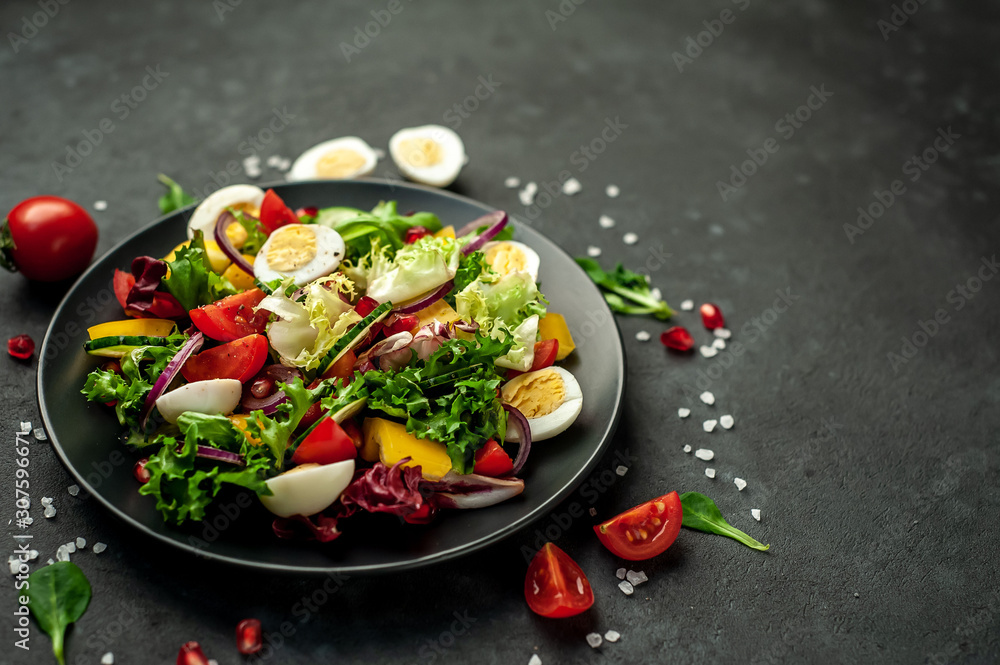 Salad with pomegranate, tomatoes, fresh cucumbers, onions, sesame seeds and cashew nuts, spices on a stone background. Healthy vegetarian food. 