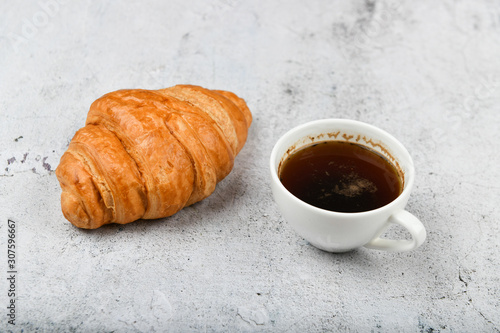 croissant and cup. on a specific background. Fresh french croissant. on a wooden background. View from above. Morning breakfast with a croissant. A French breakfast is prepared at home. on the stove a