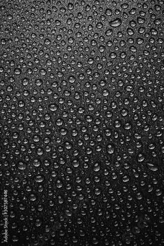 abstract background: many drops of water on a dark surface - non-stick coating in a pan. Black and white photo