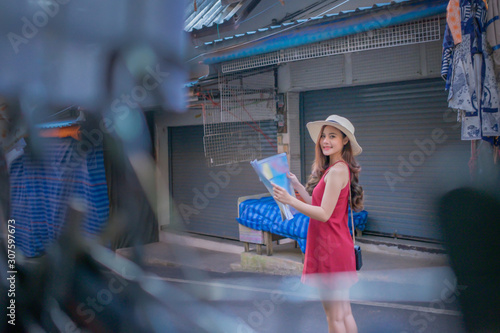 Smiling woman traveler in chiangmai market landmark chiangmai thailand holding world map with backpack on holiday, relaxation concept, travel concept photo