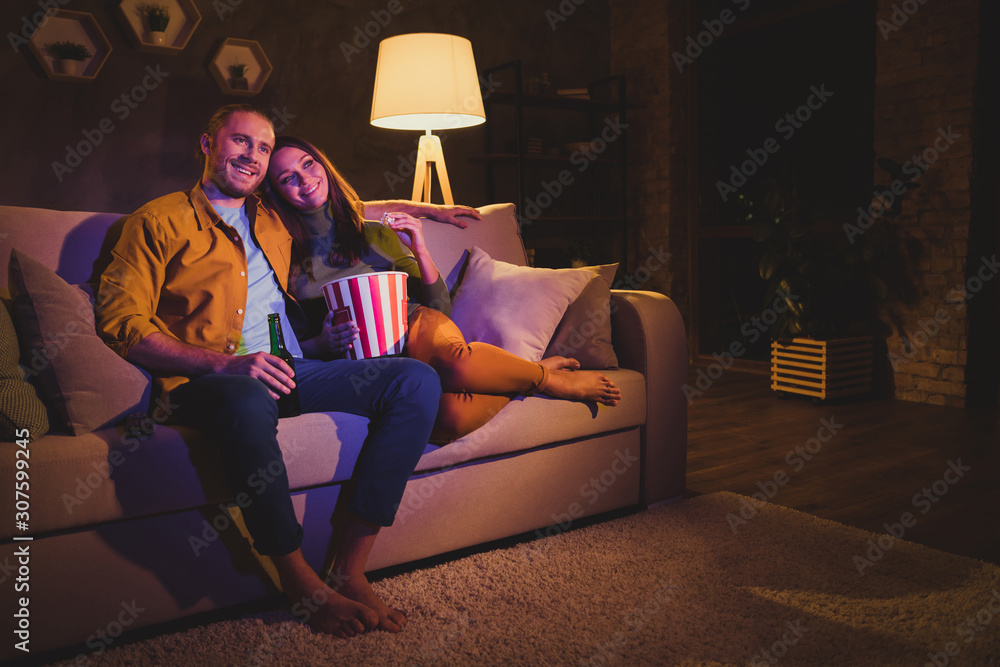 Nice attractive lovely cheerful cheery couple girl sitting on divan enjoying snack watching film spending day weekend holiday at night dark home house apartment indoors - obrazy, fototapety, plakaty 