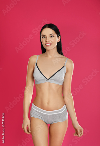 Beautiful young woman in grey sportive underwear on pink background
