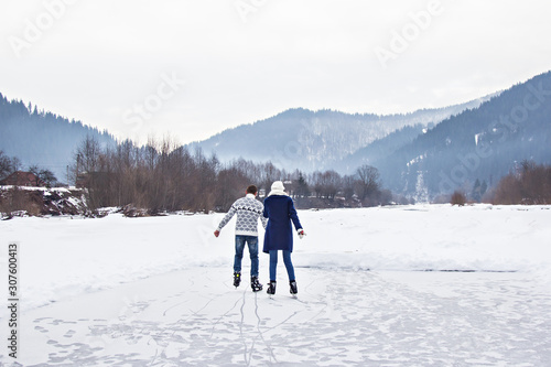 loving couple in warm sweaters skates on a frozen lake