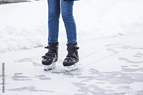 Young girl skates on ice in jeans on the nature.