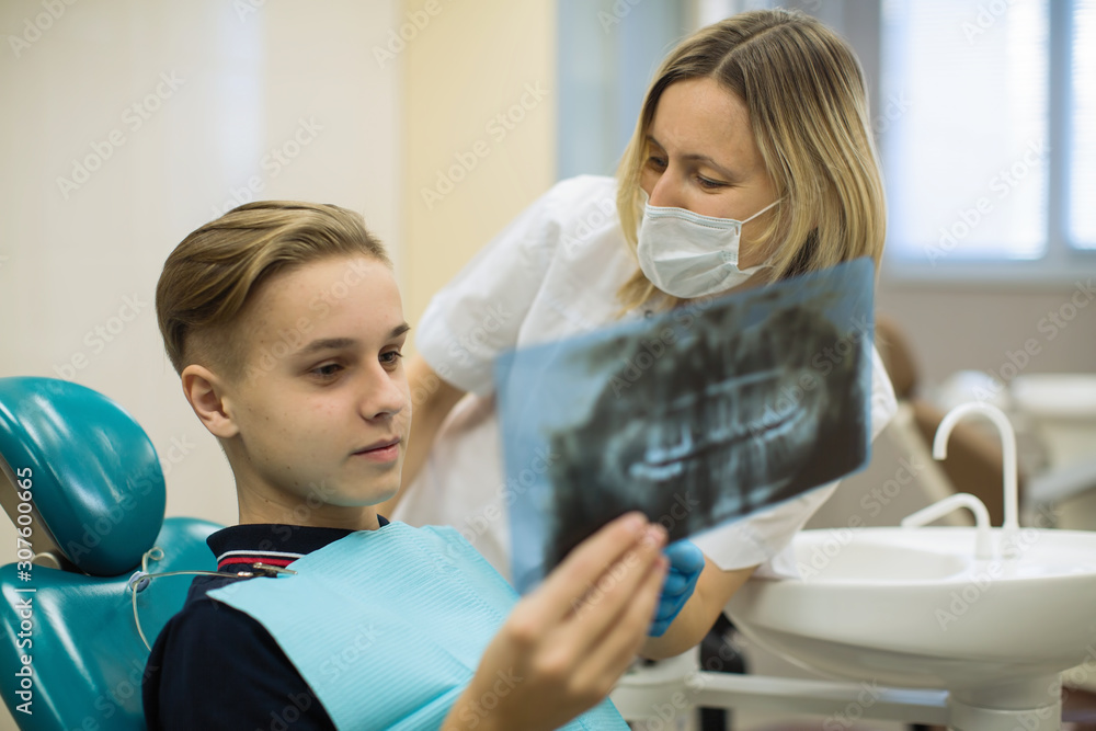 Dentist showing to young man patient x-ray the jaw at medical clinic. Stomatology medicine concept. Dentist showing to young man patient x-ray the jaw at medical clinic. Stomatology medicine concept.