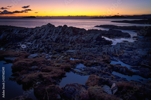 Tranquil sunset scene on rocky beach  on west coast of Scotland.Colourful sky at twilight and puddles of water among rocks during low tide.Beauty in nature.