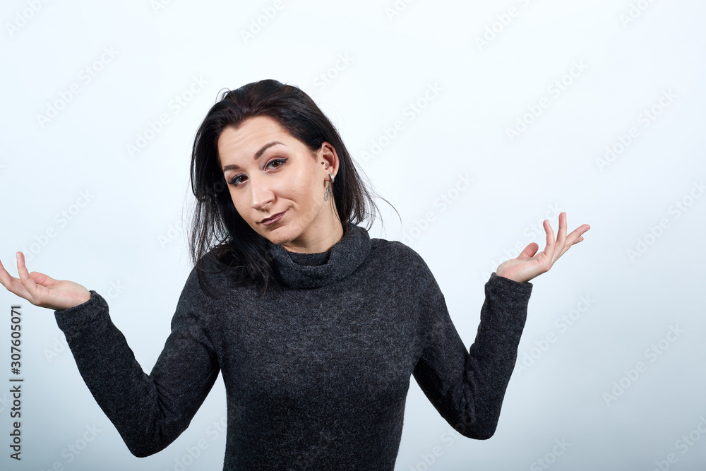 Beautiful caucasian young woman in fashion black sweater spreads hands, looking unhappy over isolated white background, Lifestyle concept Beautiful caucasian young woman in fashion black sweater spreads hands, looking unhappy over isolated white background, Lifestyle concept