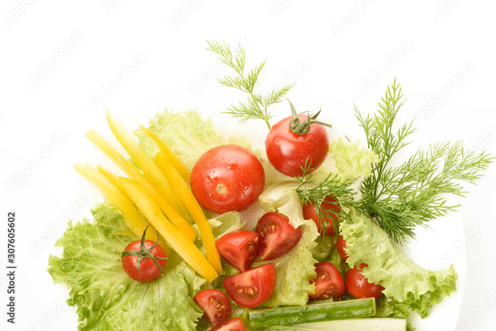 Fresh vegetables lie on the green leaves. Tomatoes, cucumbers, yellow peppers, lettuce isolated on a white background.