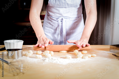 The concept of making bread, baking. Woman kneads the dough.