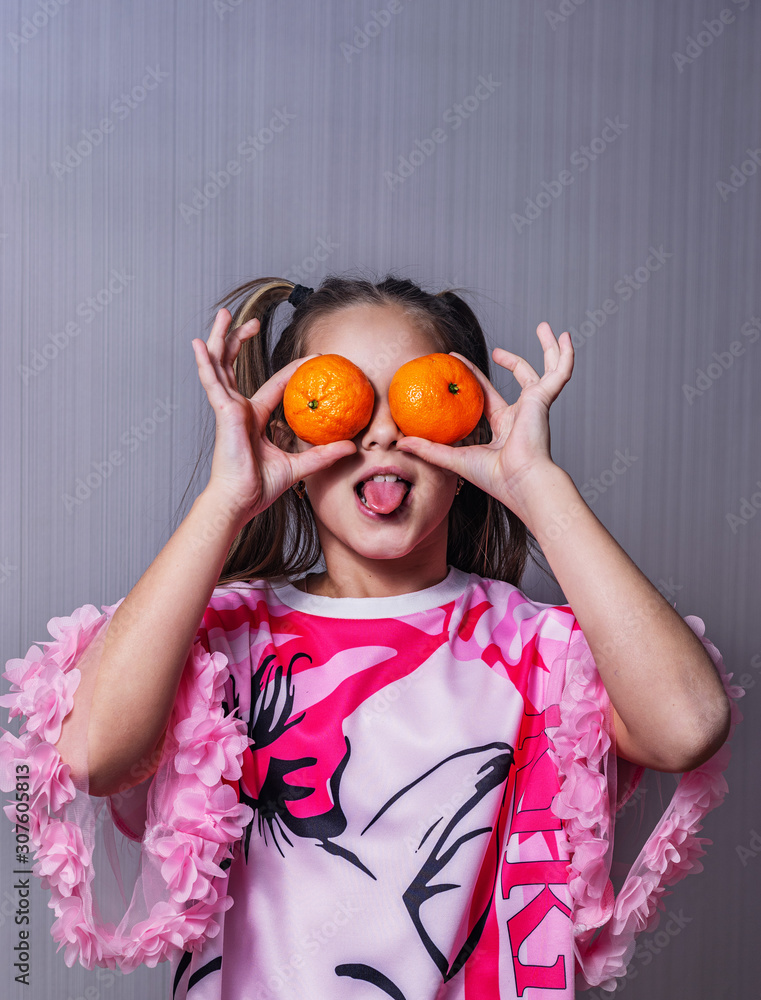 a young girl with tangerines in her hands poses for the camera a young girl with tangerines in her hands poses for the camera