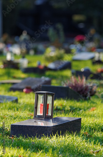 lantern on a gravestone of a cemetery with pauper graves against blurred background photo