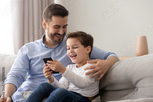 Laughing father and son using smartphone having fun in internet