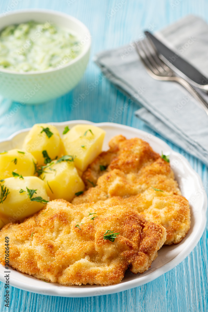 Chop pork cutlets , served with boiled potatoes and tzatziki dip. 