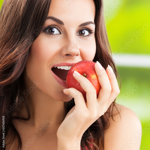 Young happy smiling lovely brunette woman with red apple