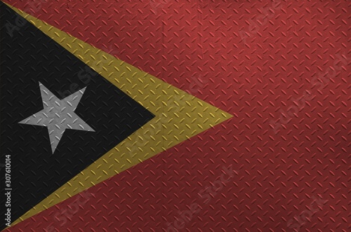 Timor Leste flag depicted in paint colors on old brushed metal plate or wall closeup. Textured banner on rough background photo