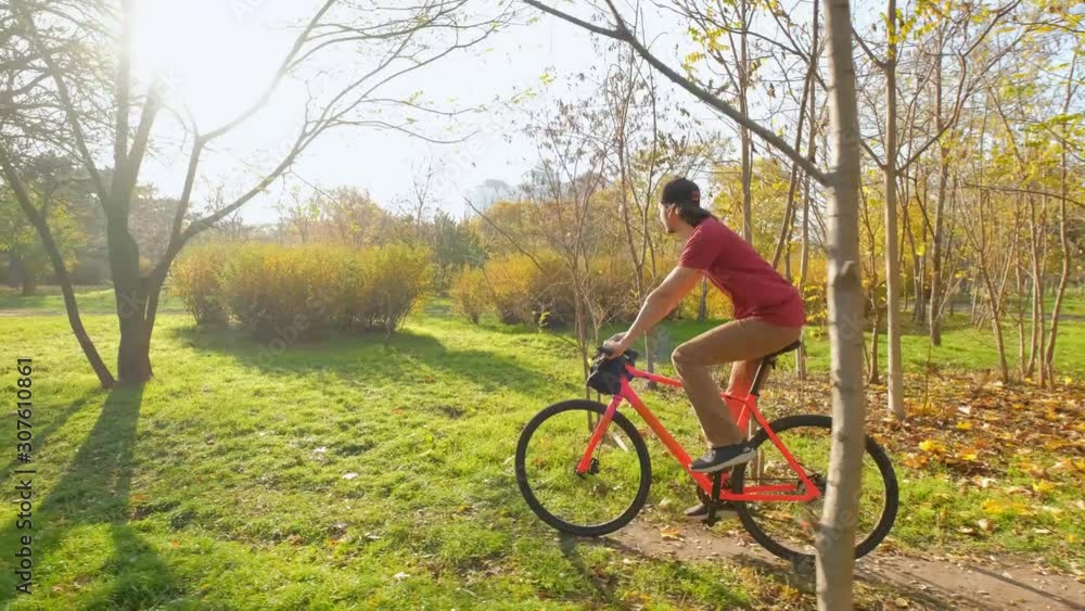 Young male with colorful bicycle ride in sunny autumn park	