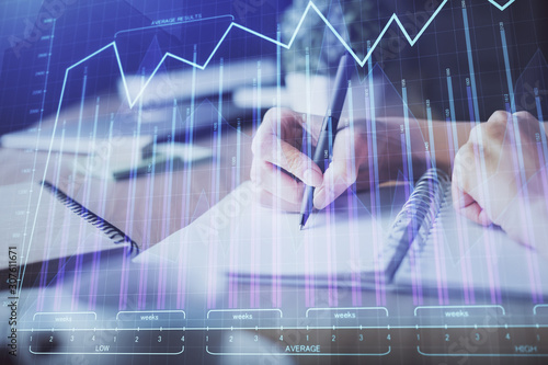 Financial forex graph drawn over hands taking notes background. Concept of research. Multi exposure