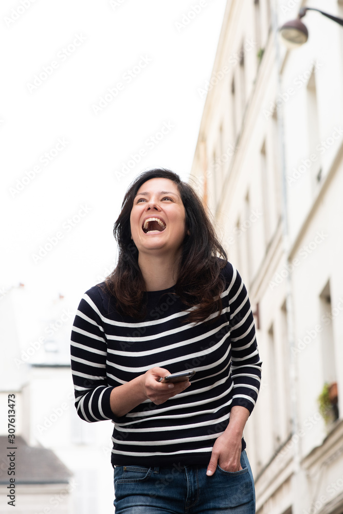 young woman in city laughing with cellphone